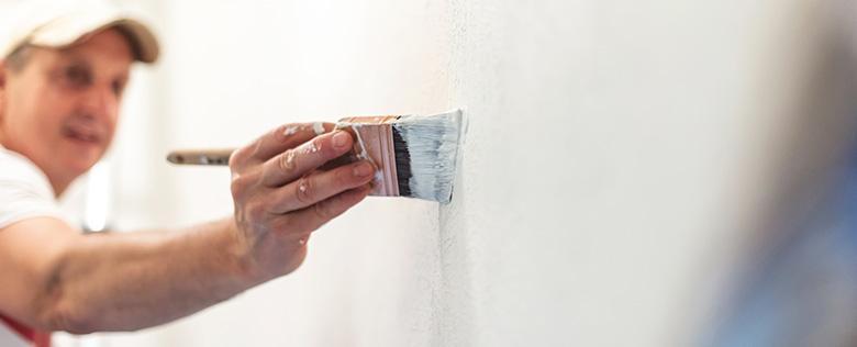 mężczyzna maluje pędzlem ścianę